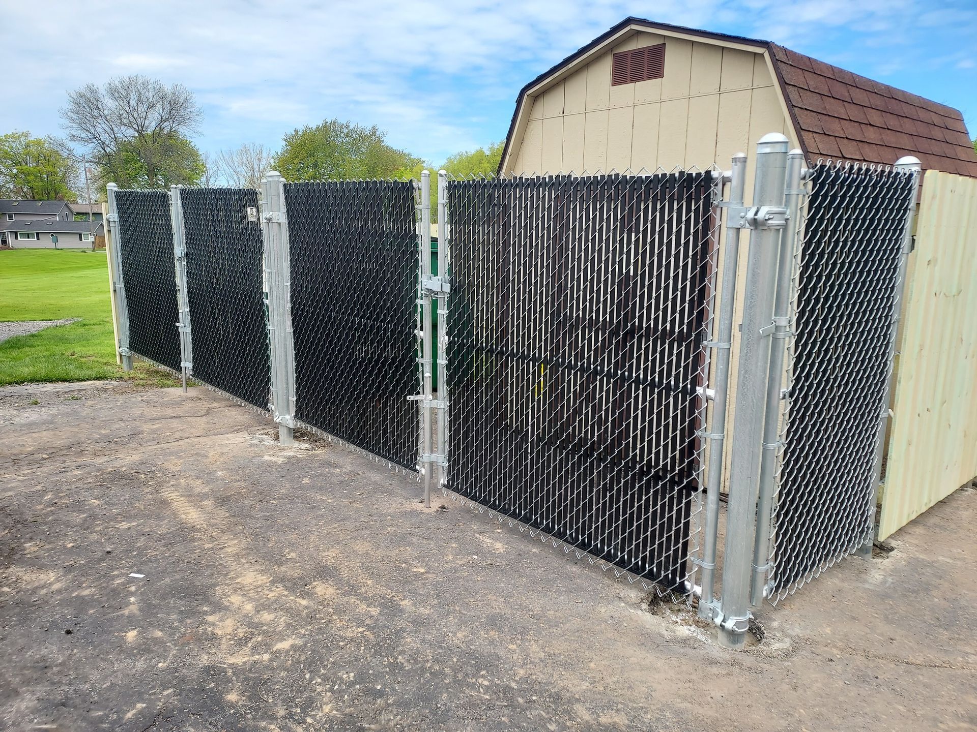 A person is holding onto a chain link fence in front of a basketball court.