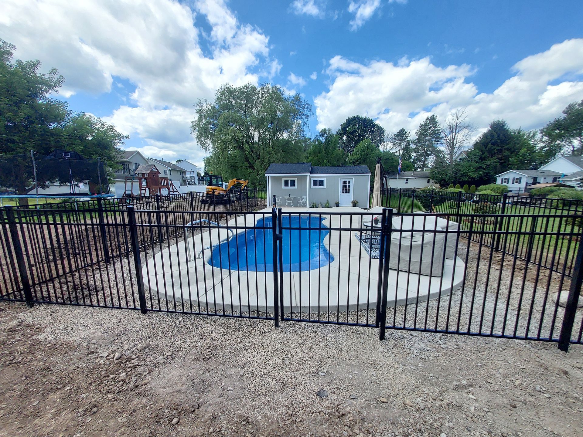 A black fence surrounds a lush green field