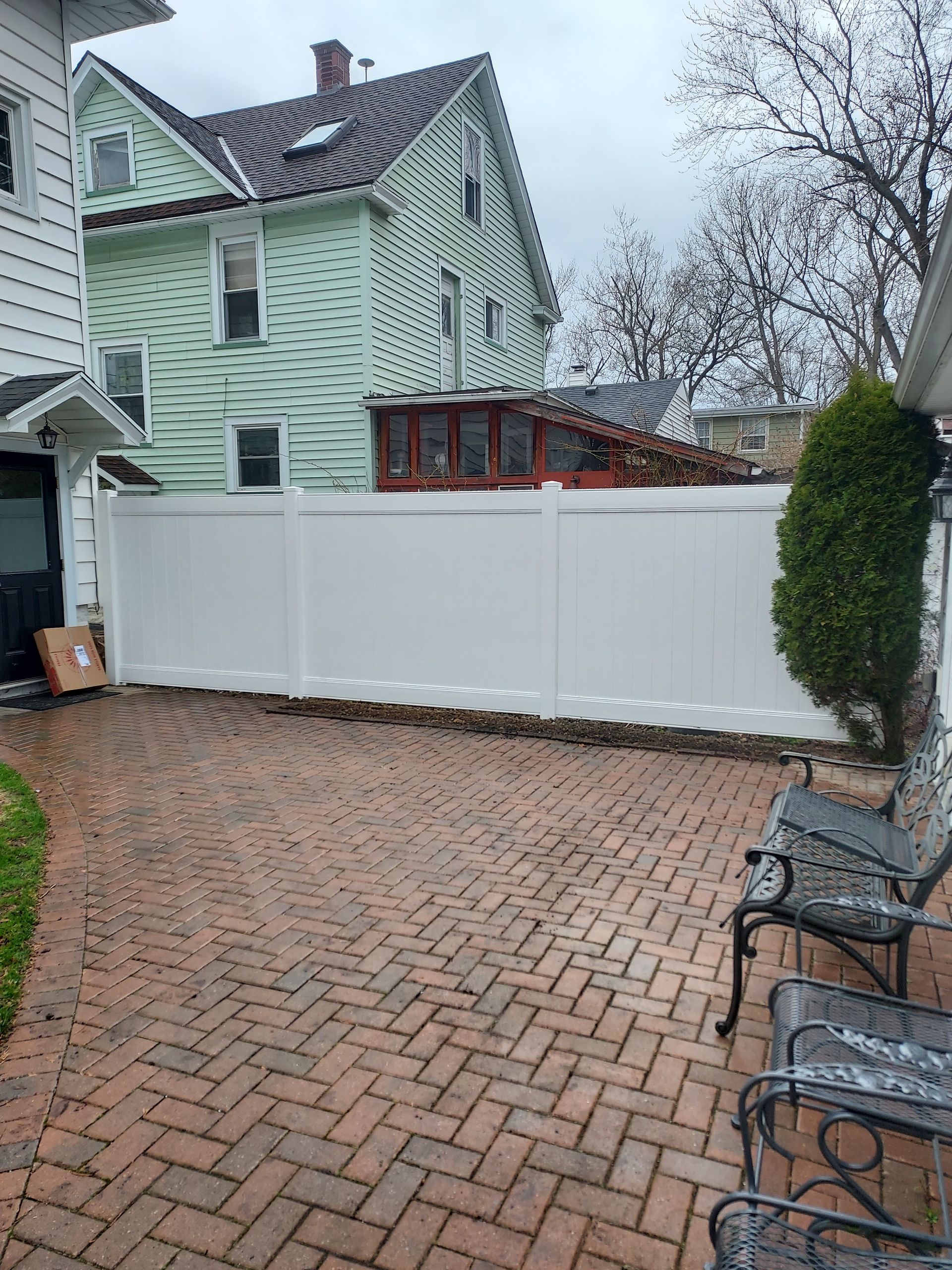There is a white fence in the backyard of a house.