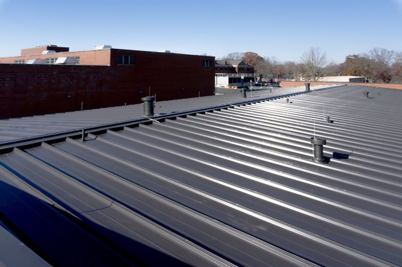 A low-angle shot of a dark, corrugated commercial metal roof replacement