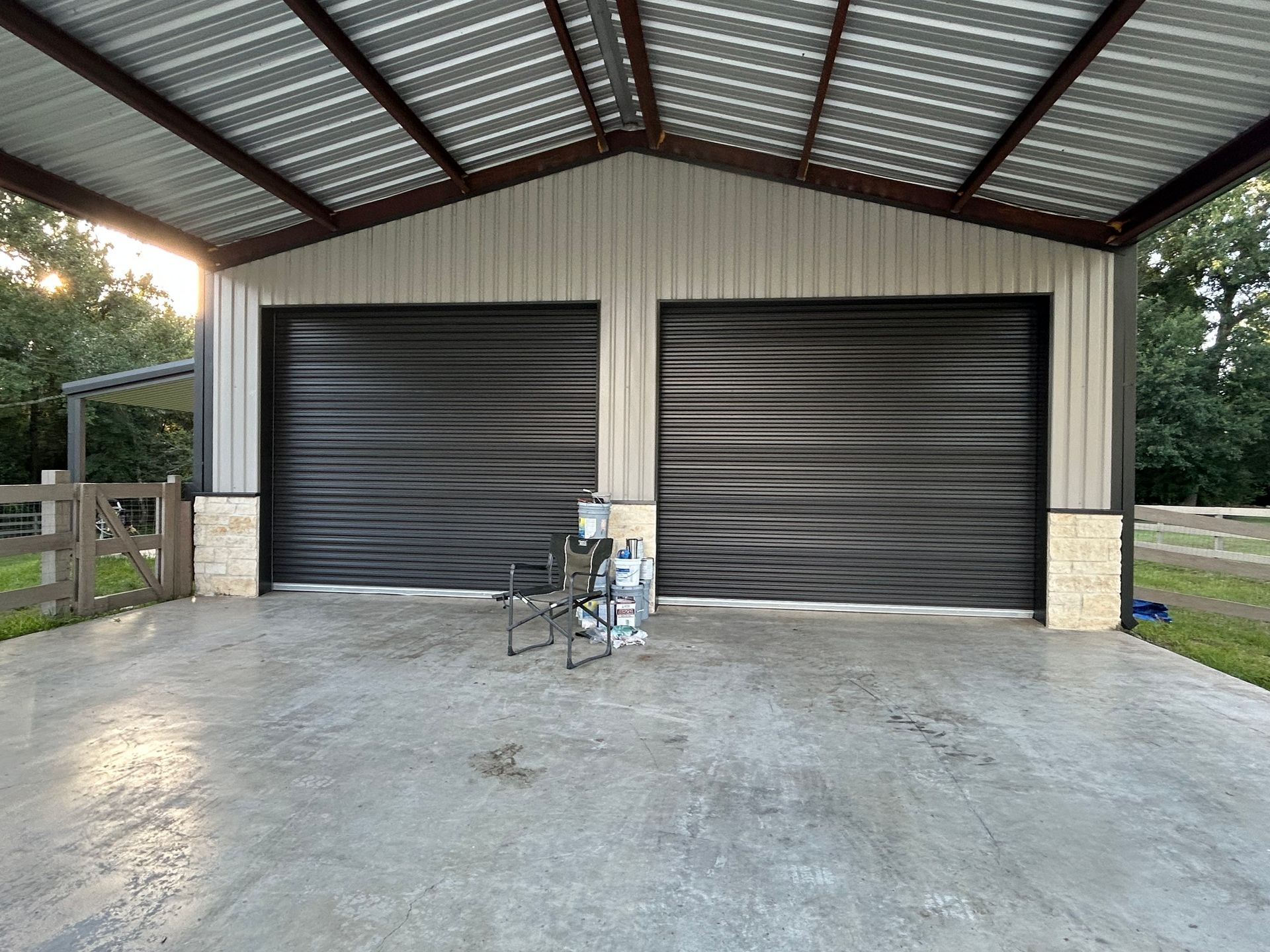 A two-bay garage with black garage doors, a metal roof, and concrete flooring. New construction.