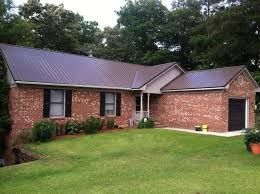 A brick house with a brown metal roof replacement