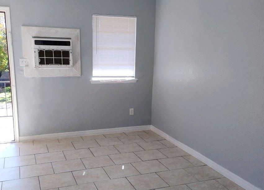 Room with gray walls, tiled floor, window, and wall-mounted air conditioner.