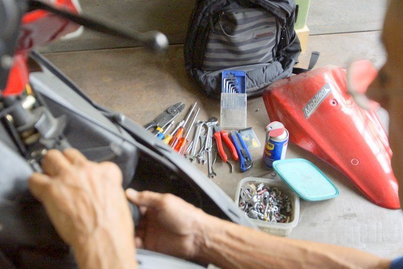 Une personne travaille sur une moto dans un garage.