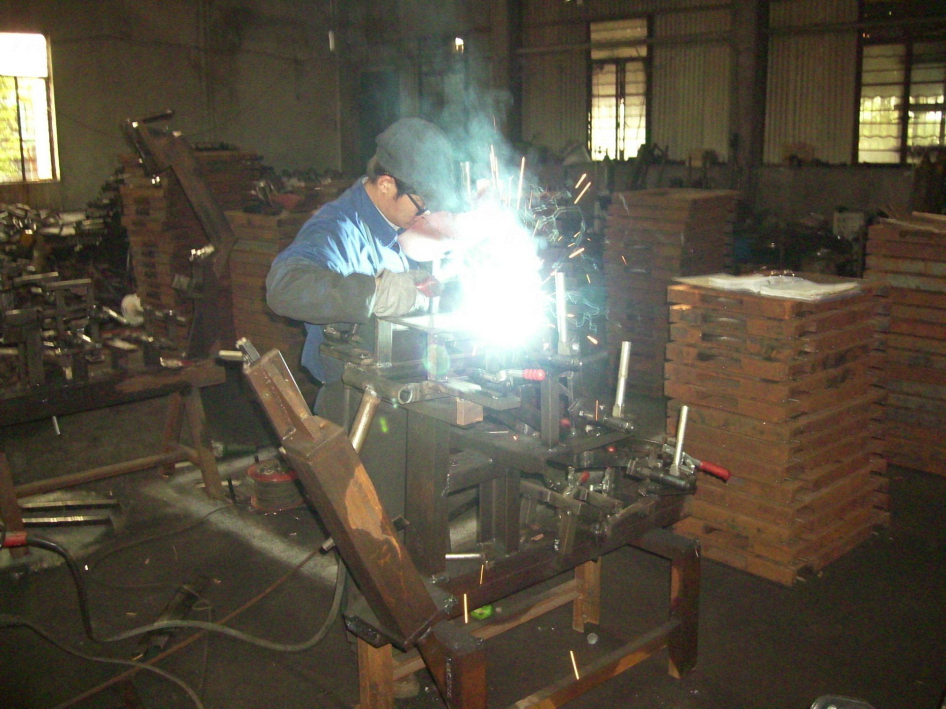 Un homme soude un morceau de métal dans une usine