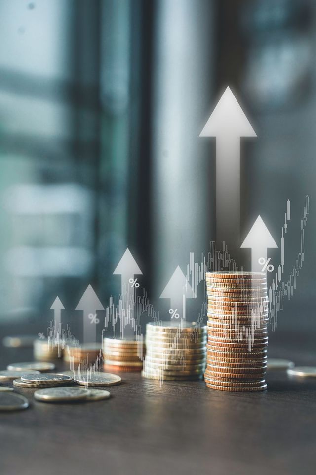 Pile di monete con frecce rivolte verso l'alto, che simboleggiano la crescita finanziaria.