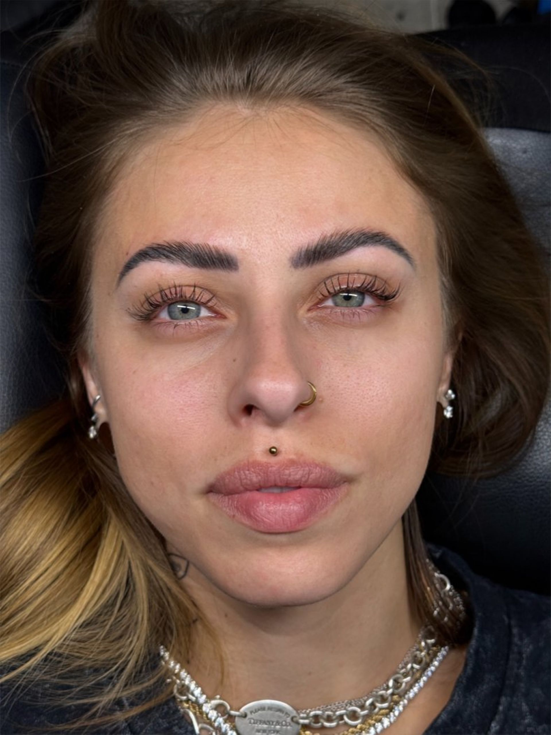 A close up of a woman 's face with a nose ring.