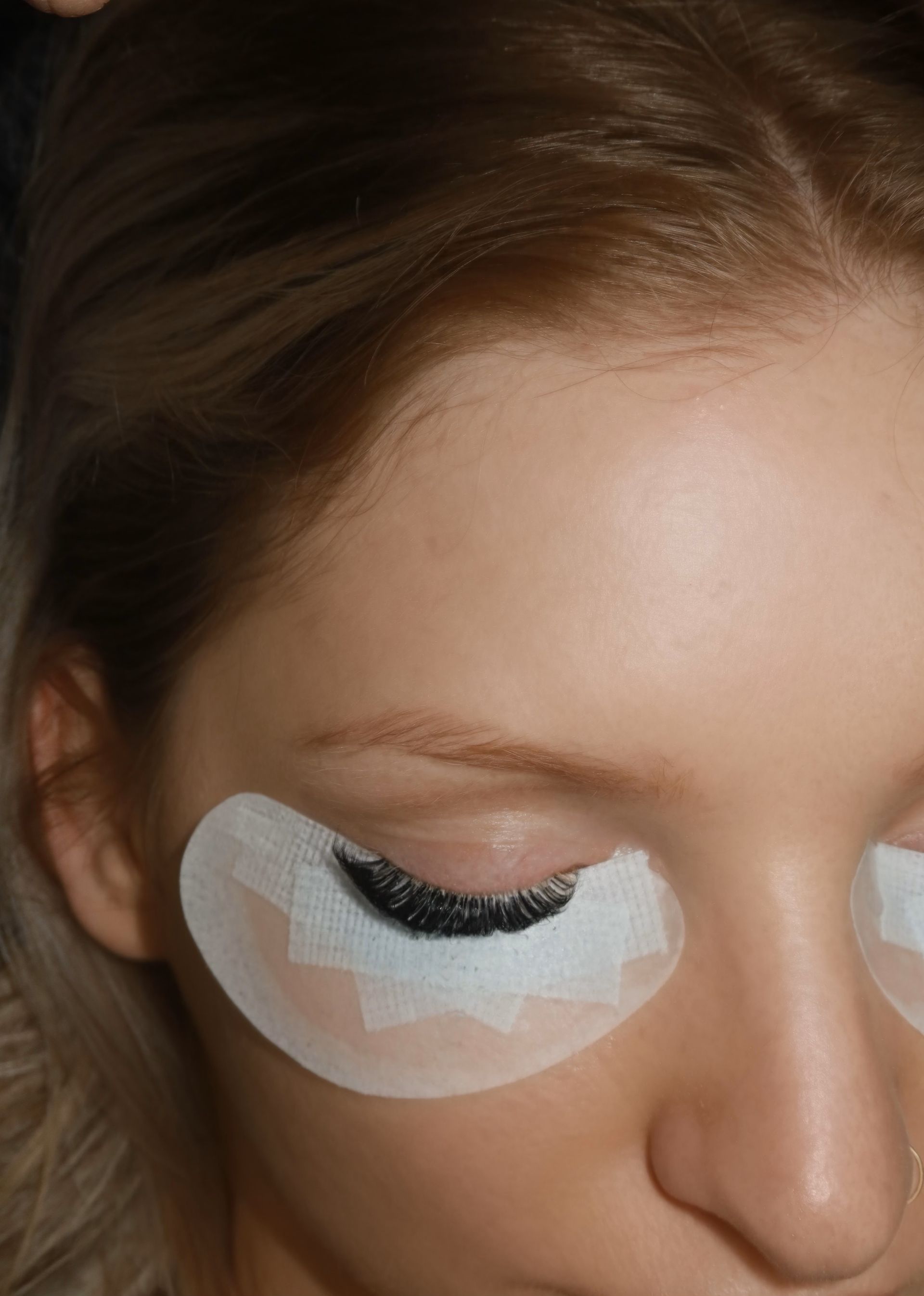 A close up of a woman 's face with tape on her eyes.