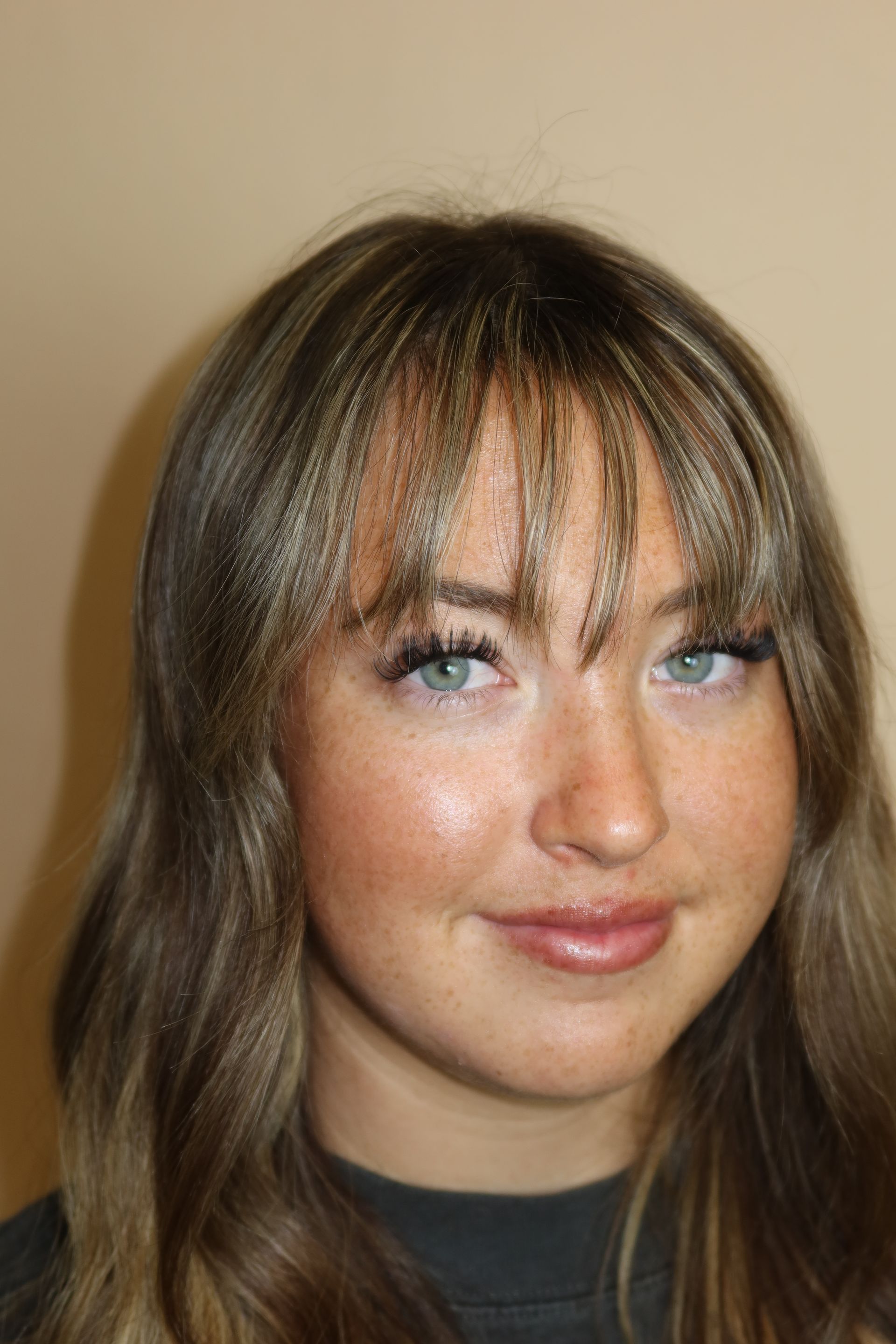 A close up of a woman 's face with long hair and bangs.