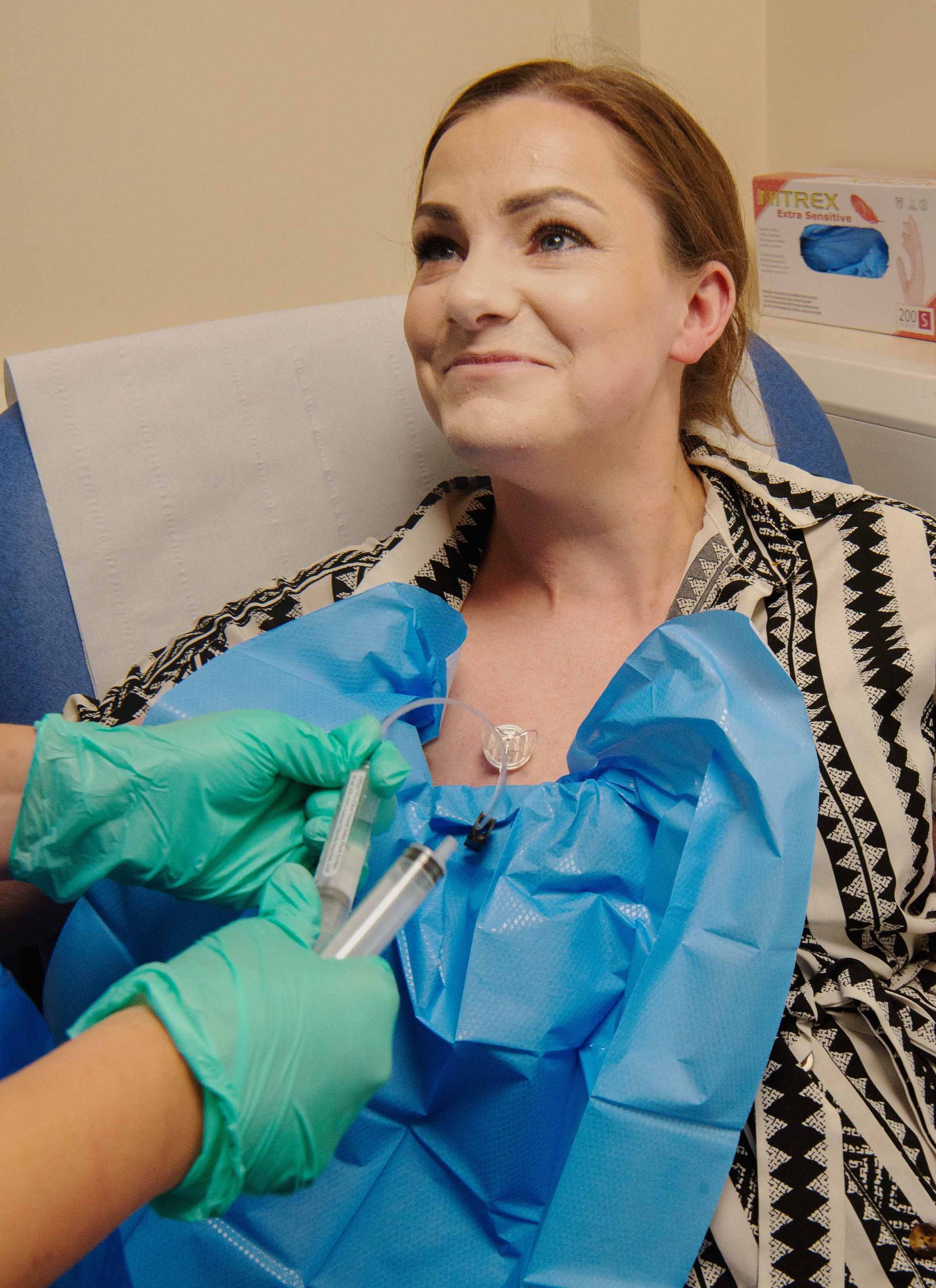 A woman is smiling while getting care from her nurse