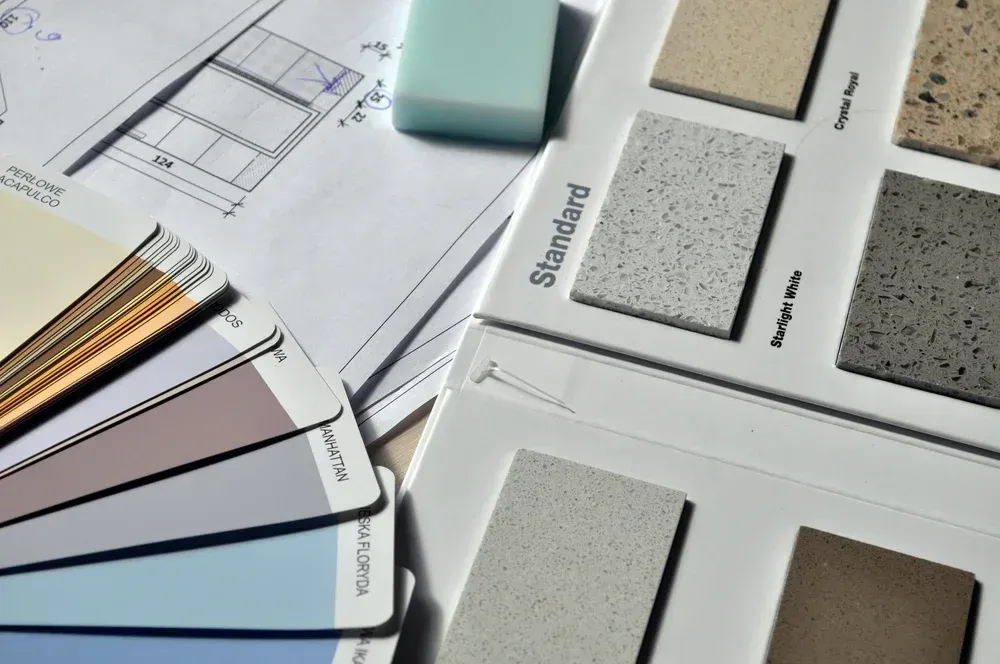 Architectural design tools: blueprints, paint swatches, and countertop samples.