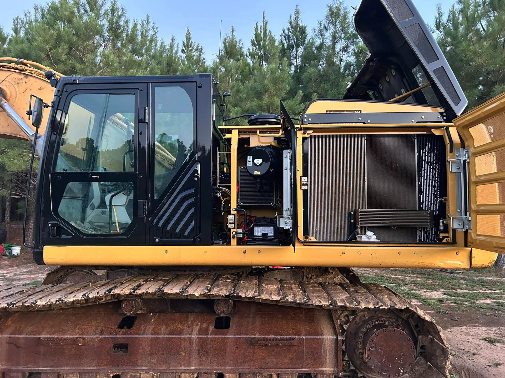 Yellow and black excavator with opened side panels, revealing engine components.