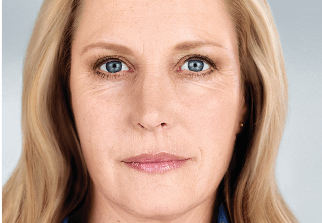 A woman with blonde hair and blue eyes is looking at the camera.