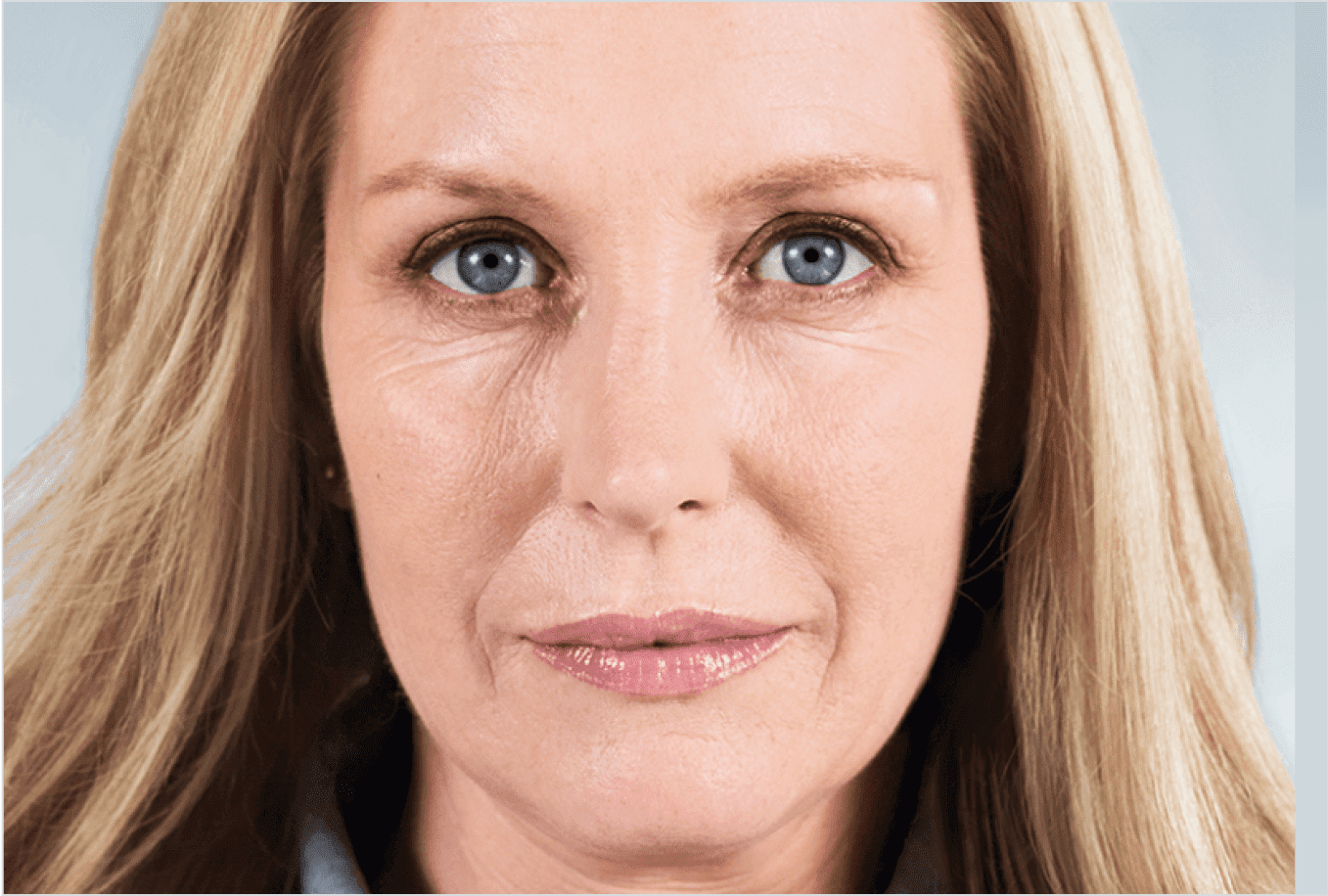 A close up of a woman 's face with wrinkles and blue eyes.