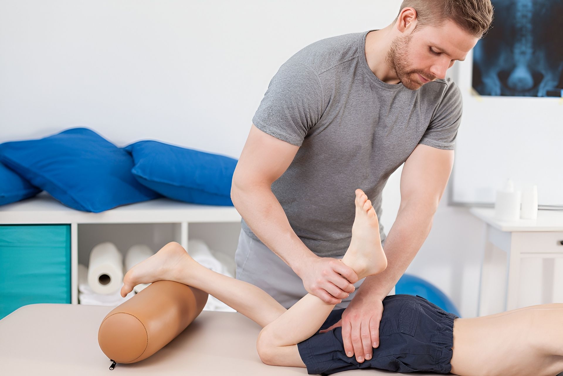 Physical Therapist Stretching Patient's Leg on a Table — Dive Chiropractic in Mermaid Beach, QLD