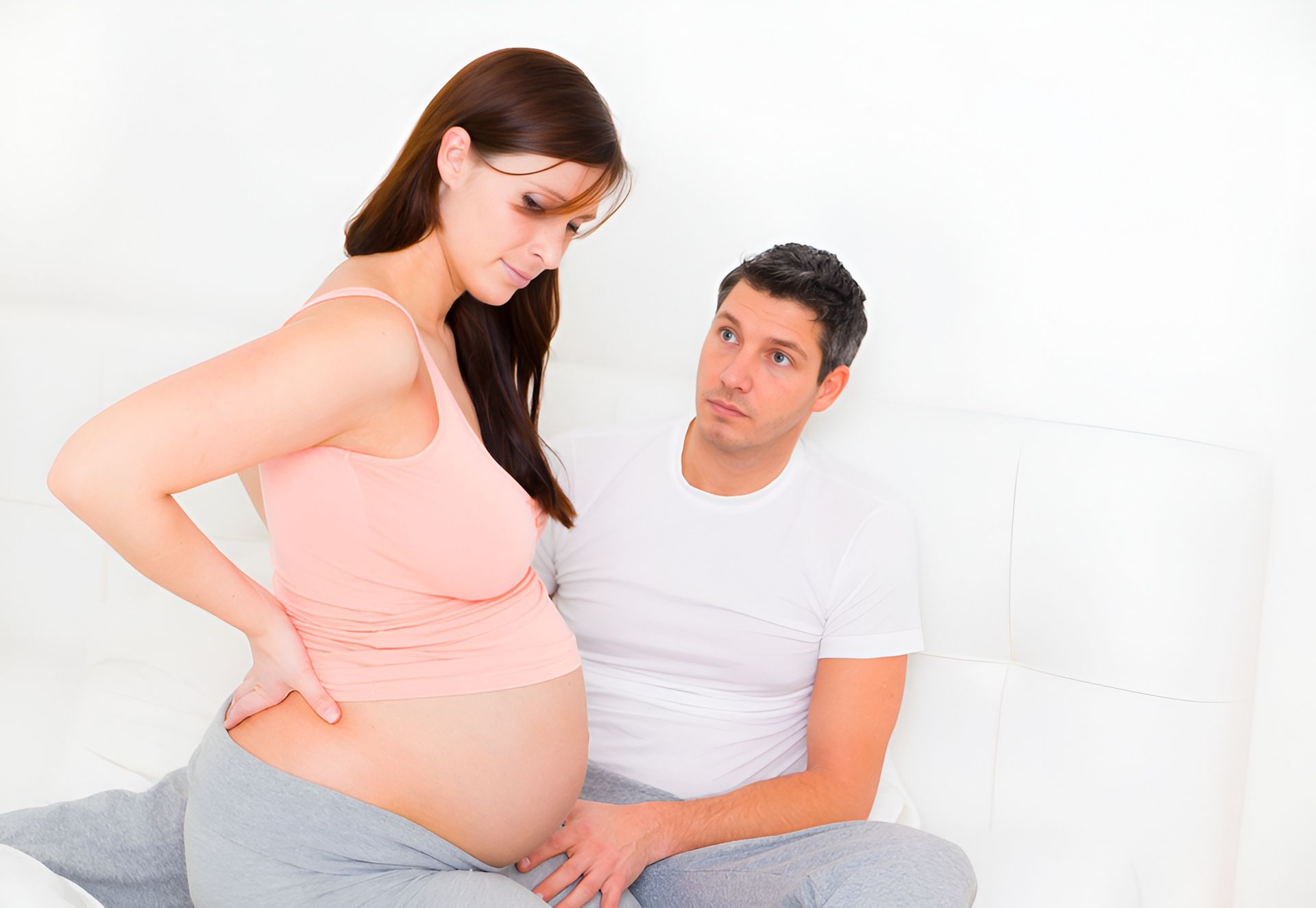 Pregnant Woman Holding Back, Man Looks Concerned — Dive Chiropractic in Mermaid Beach, QLD