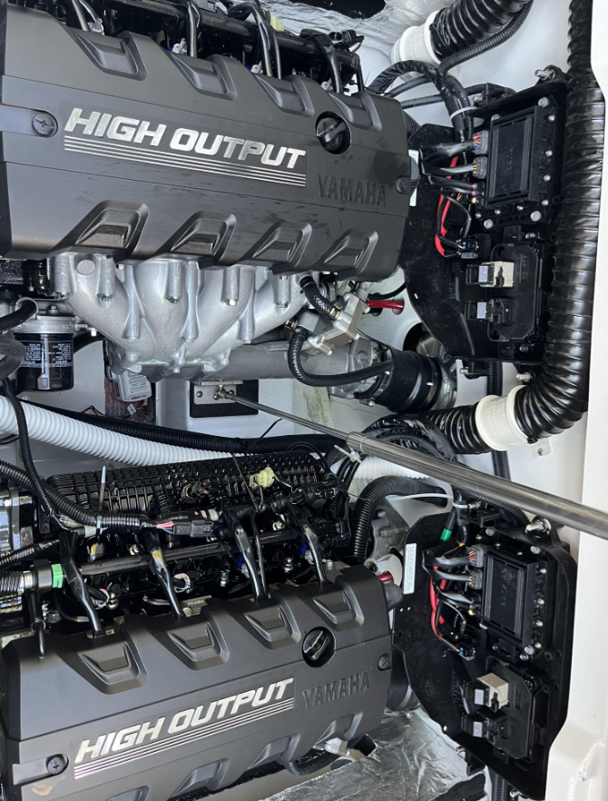 Two Yamaha High Output boat engines, black and silver, installed in a white compartment.