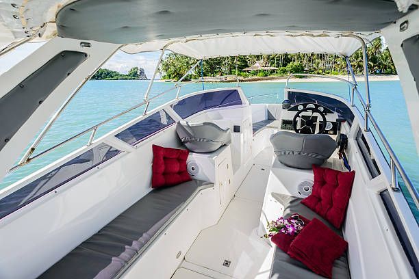 Interior of a speedboat with gray and red cushions, tropical scenery visible in the background.