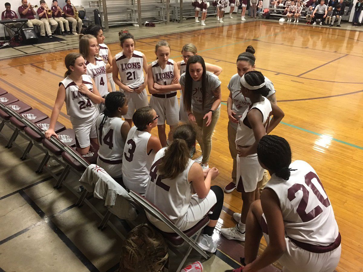 a group of female basketball players are huddled together on the court .