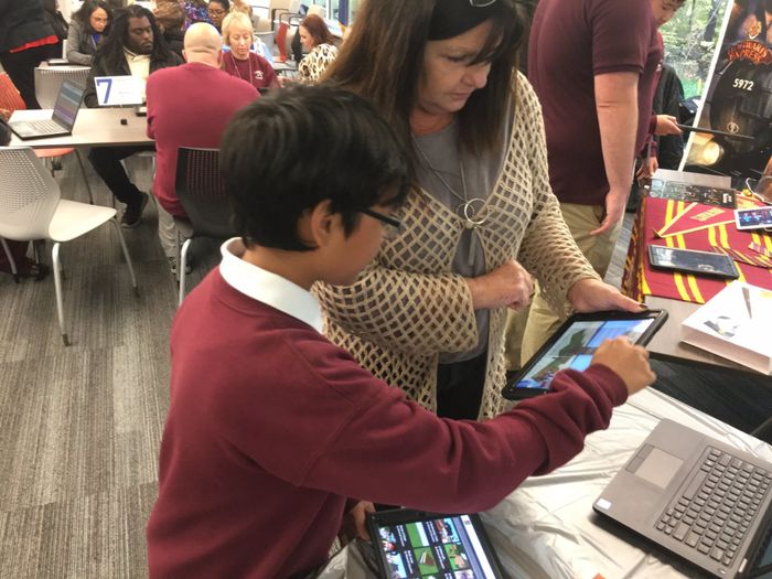 a woman and a boy are looking at a tablet computer .