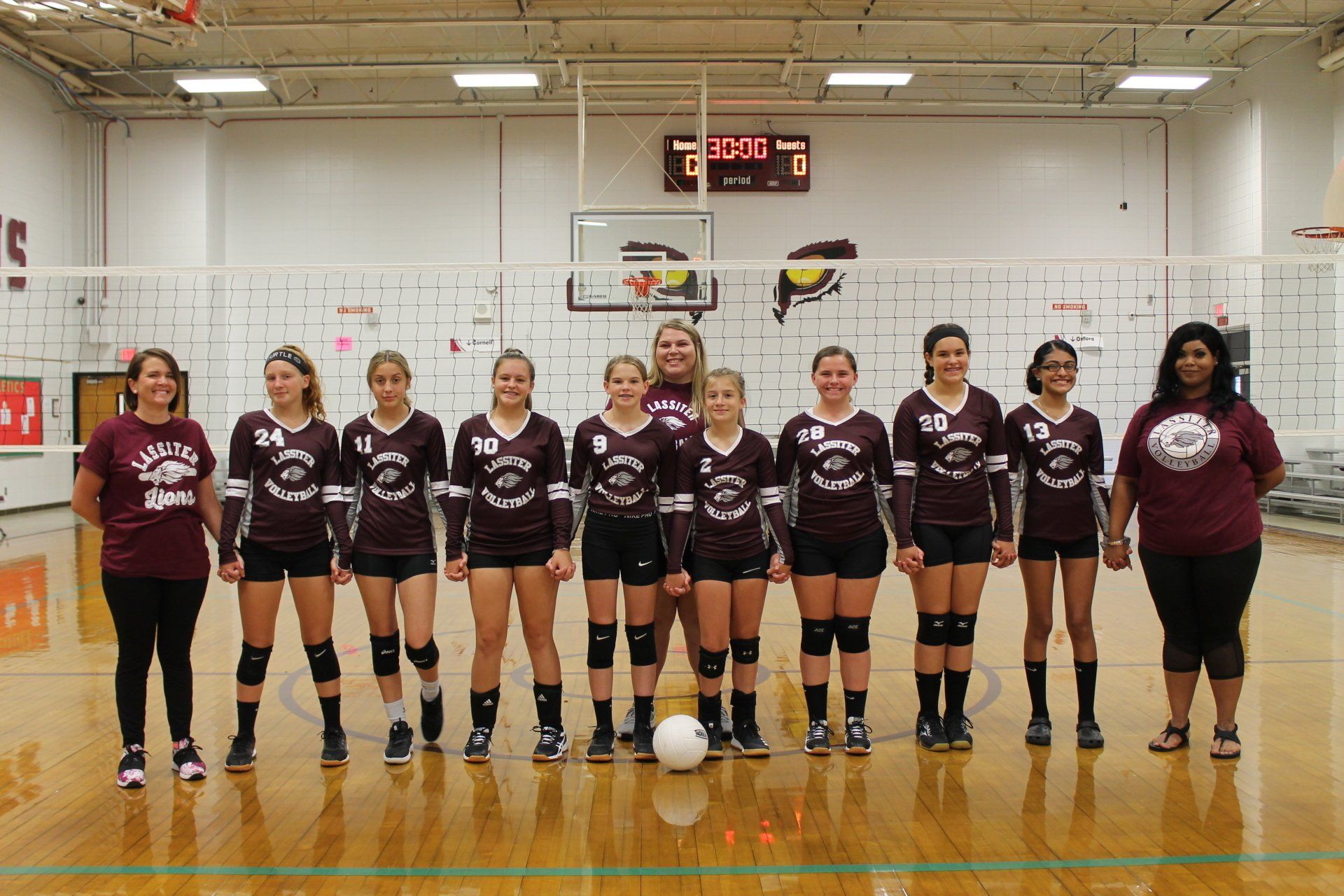 a volleyball team is posing for a picture in a gym .