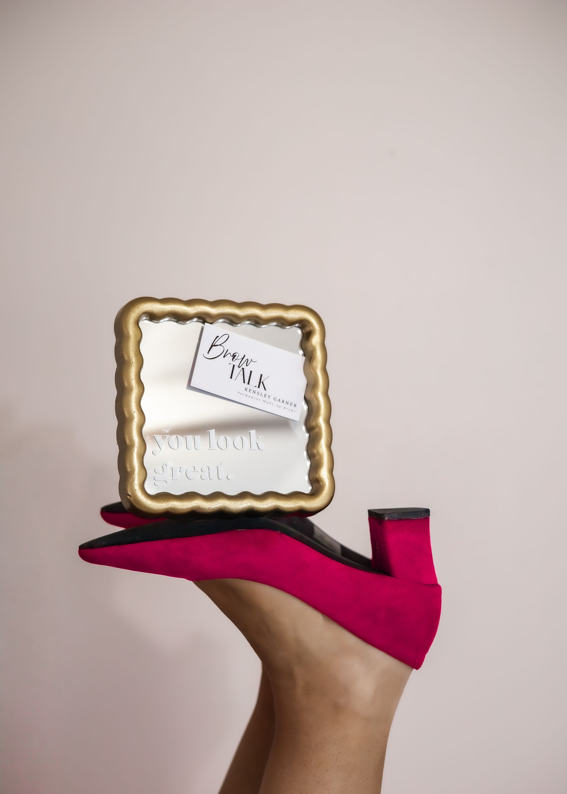 Woman with brown hair laughs, eyes closed, mouth wide. She wears a green shirt in front of a white background.
