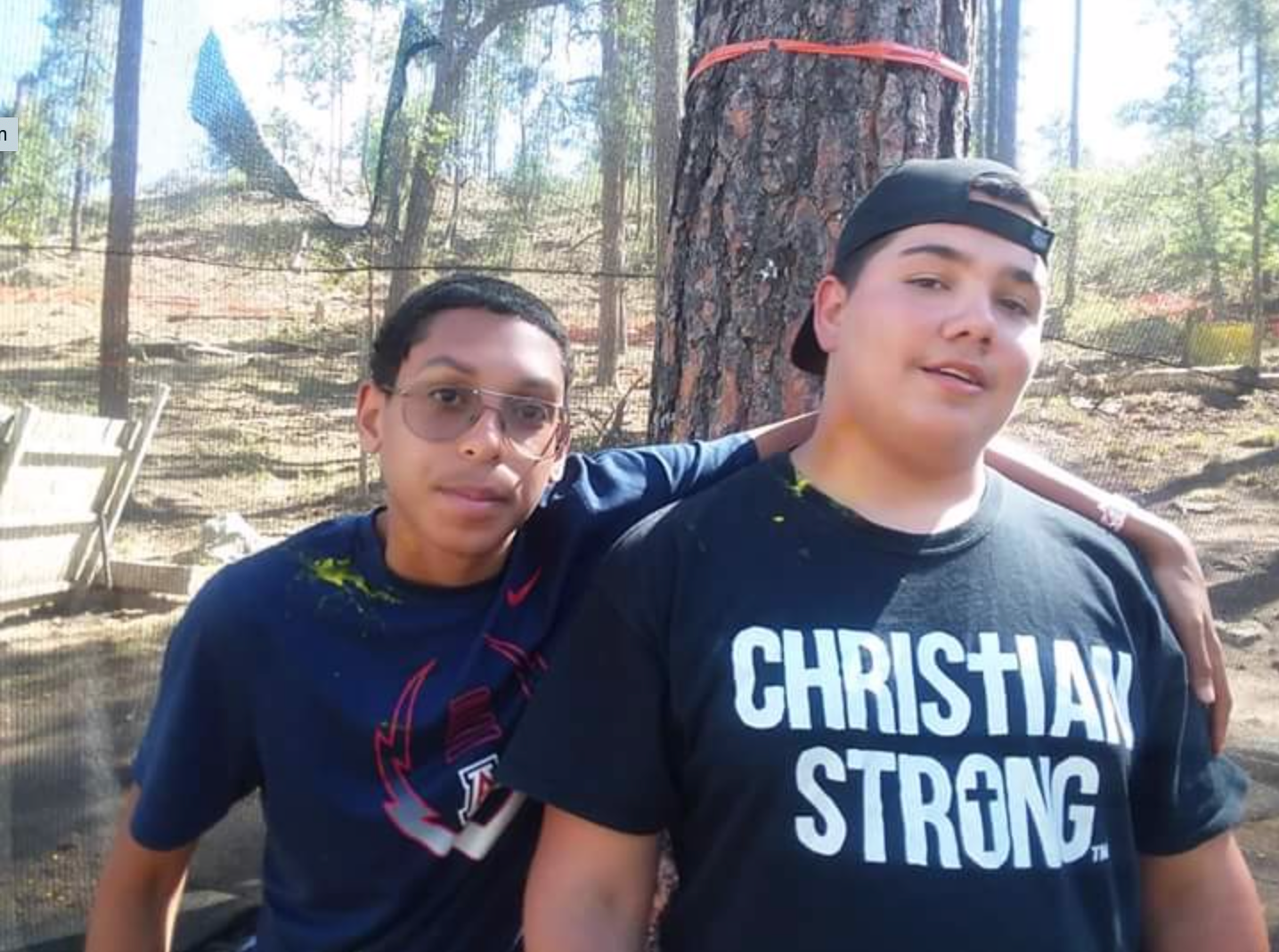 Two boys posing for a picture one wearing a christian strong shirt
