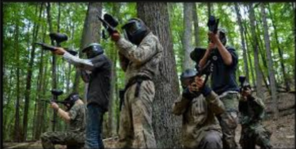 A group of people are playing paintball in the woods