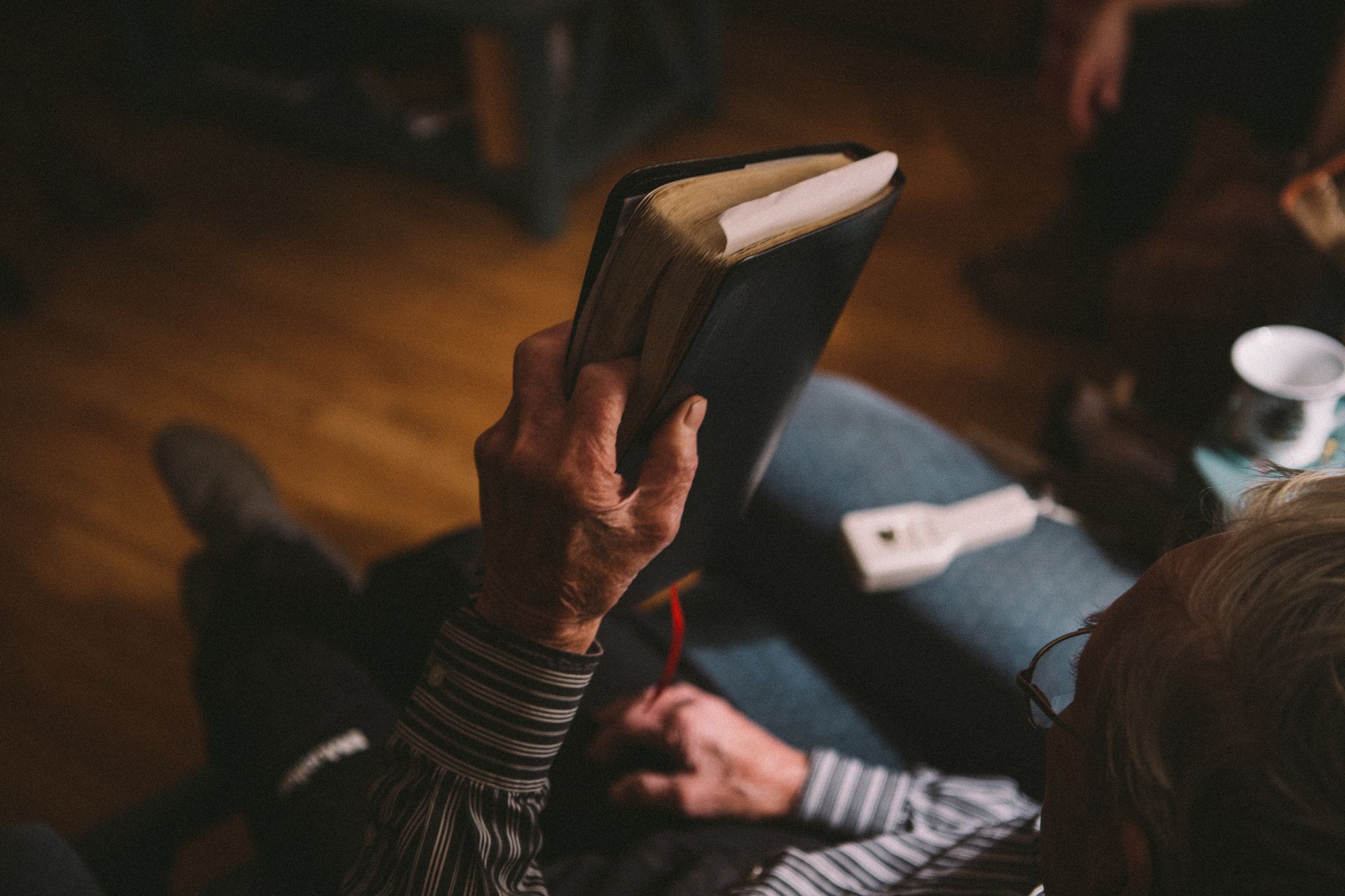 A man is sitting on a couch reading a bible.