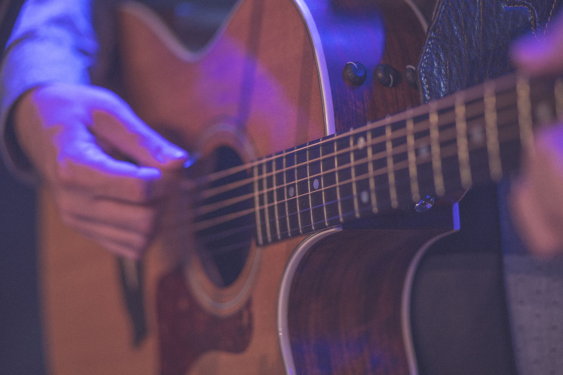 A close up of a person playing an acoustic guitar on a stage.