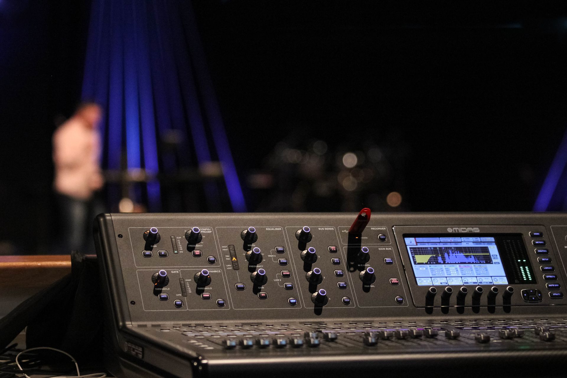 A man is playing drums in the background behind a mixer