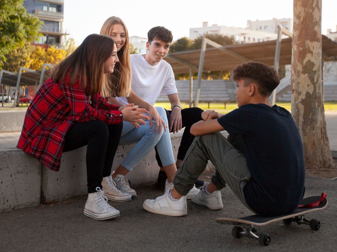 A group of young people are sitting on a ledge talking to each other.