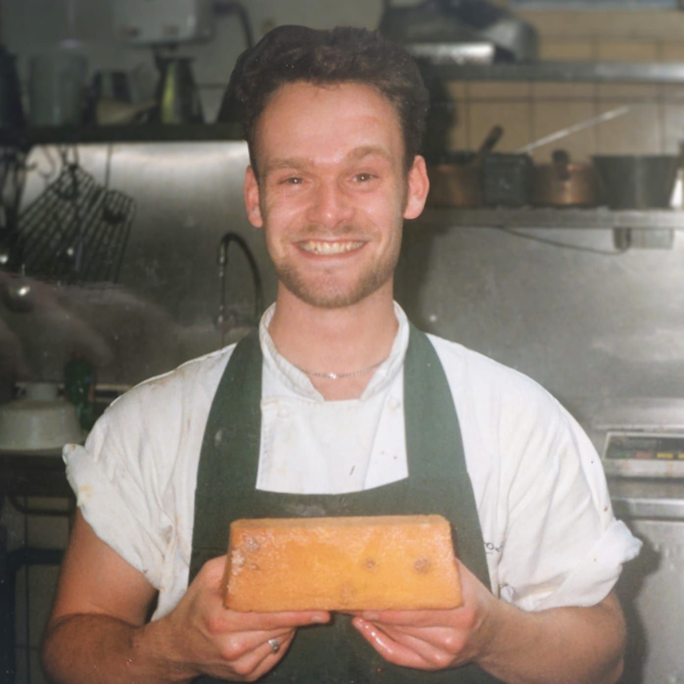 Sebastiaan Zweep in zijn tijd als patissier, lachend in de keuken en een zelfgemaakt gebakje vasthou