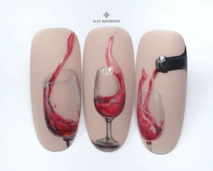 Nail art: wine glasses with red wine pouring, on a light peach background.