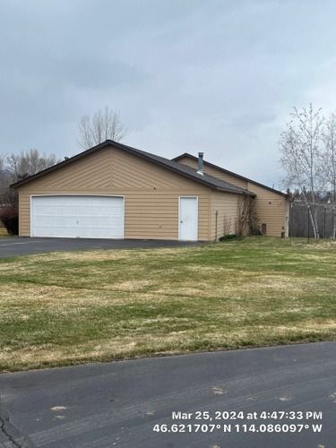 A large house with a garage and a lot of grass in front of it.