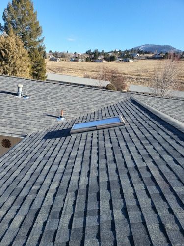 A roof with a skylight on it and a field in the background.
