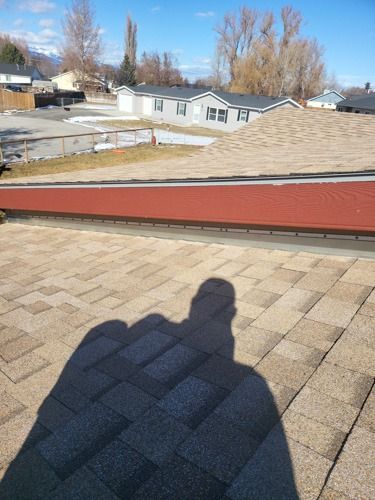 A shadow of a person is cast on the roof of a house.