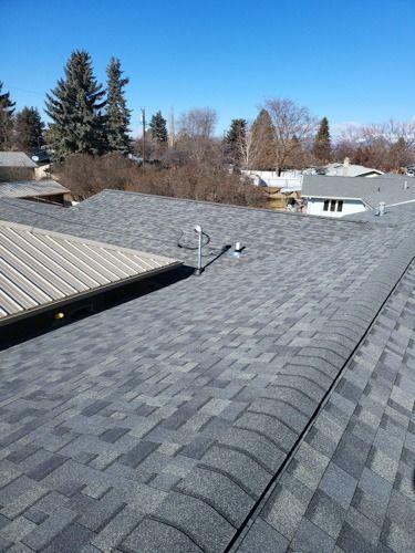 A roof with a lot of shingles on it and trees in the background.