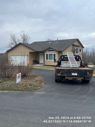 A truck with a ladder in the back is parked in front of a house.