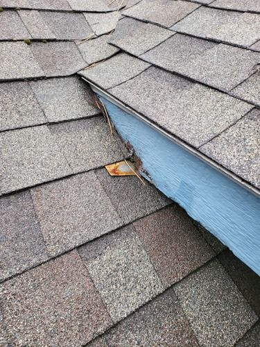 A close up of a roof with shingles and a blue trim.
