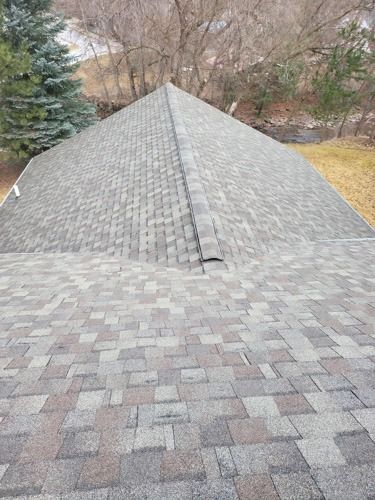 A roof with a lot of shingles on it and trees in the background.