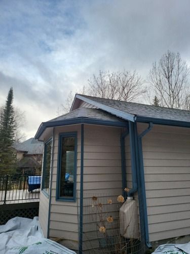 A small house with a blue gutter and a window.