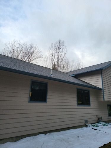 A house with a roof that is covered in snow and trees in the background.