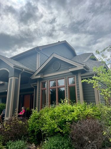 A large house with a lot of windows and bushes in front of it.