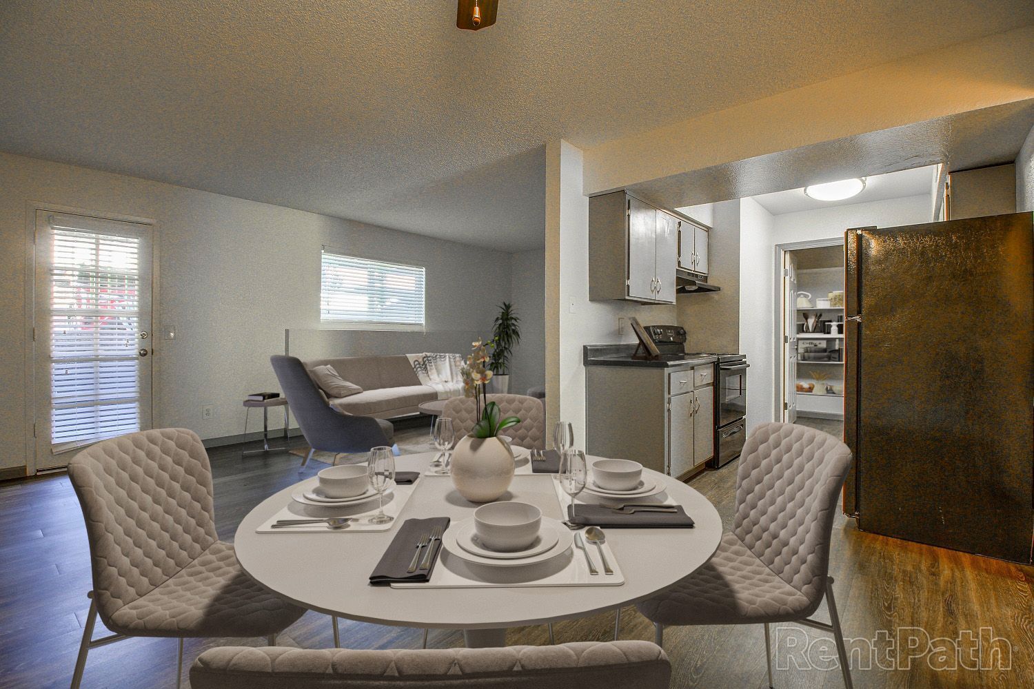 Dining area with round table set for a meal, opening to a living room and kitchen.