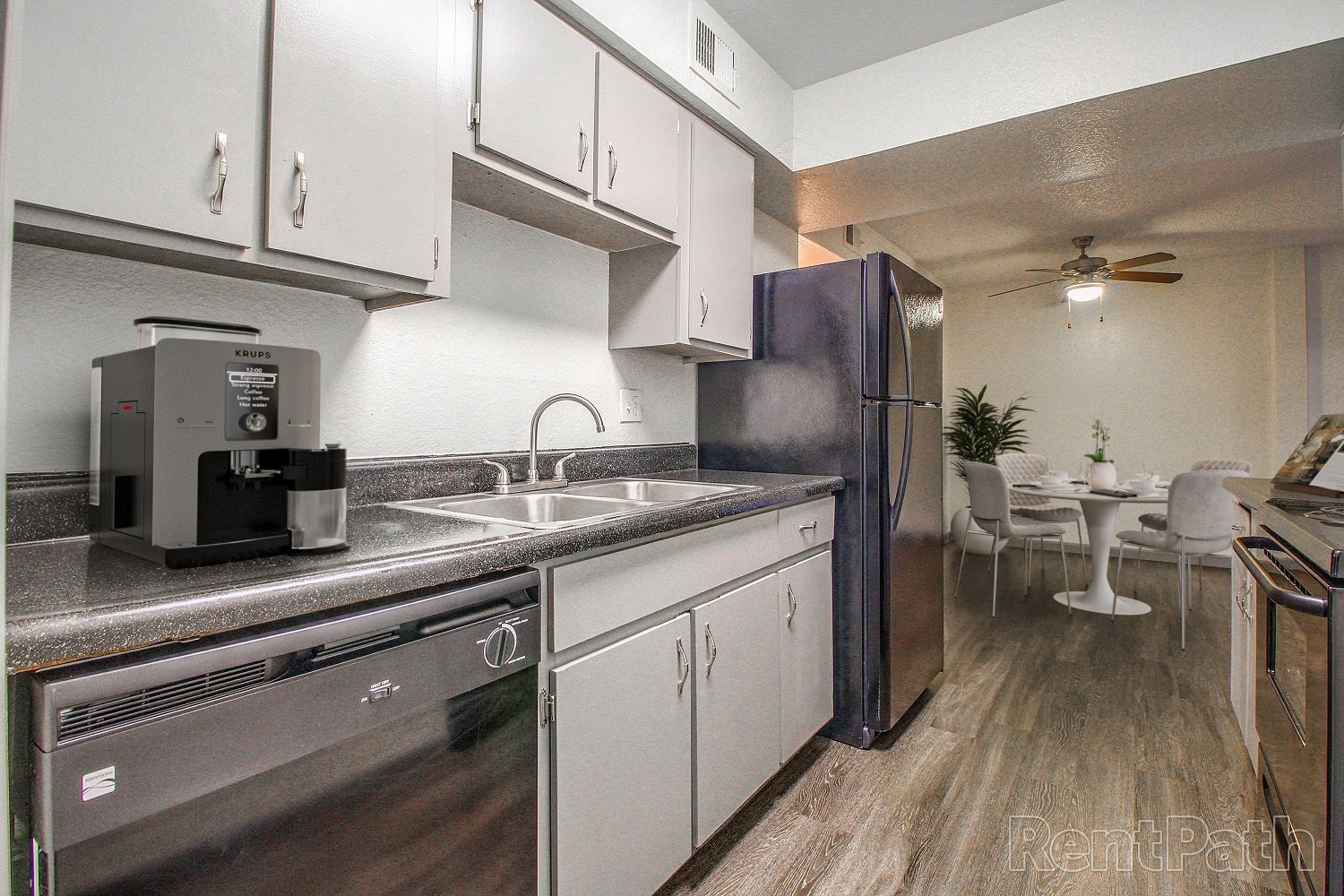 Kitchen with gray cabinets, stainless steel appliances, and a dining area in the background.