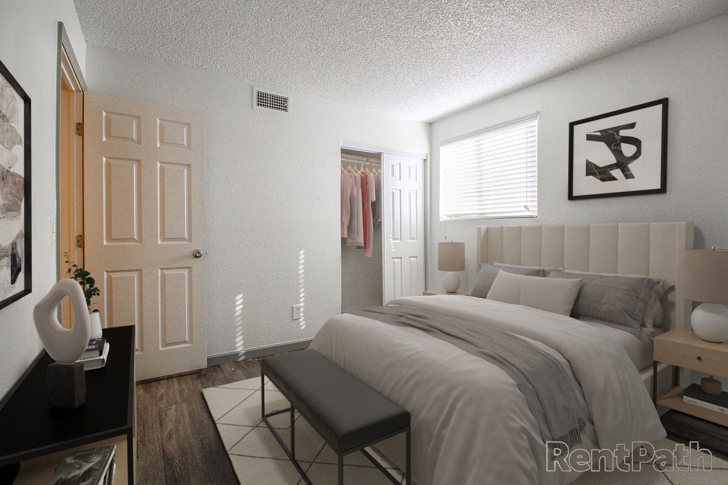 Bedroom with bed, closet, and nightstand; neutral color palette with artwork and wood flooring.
