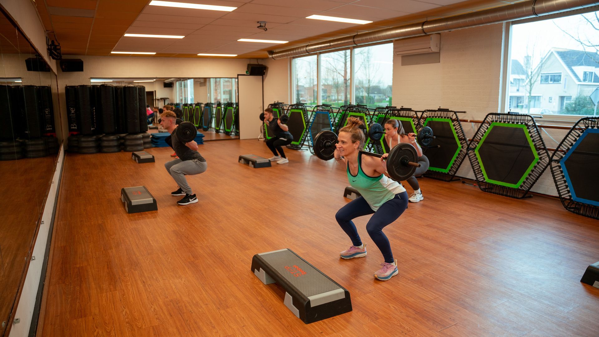 Een groep mensen doet squats in een sportschool.