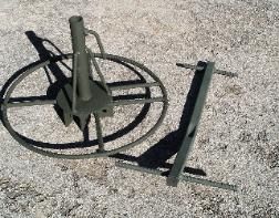 A metal object is sitting on the ground with a shadow on the ground.