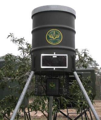 A large black barrel with a crown on it is sitting in a field.